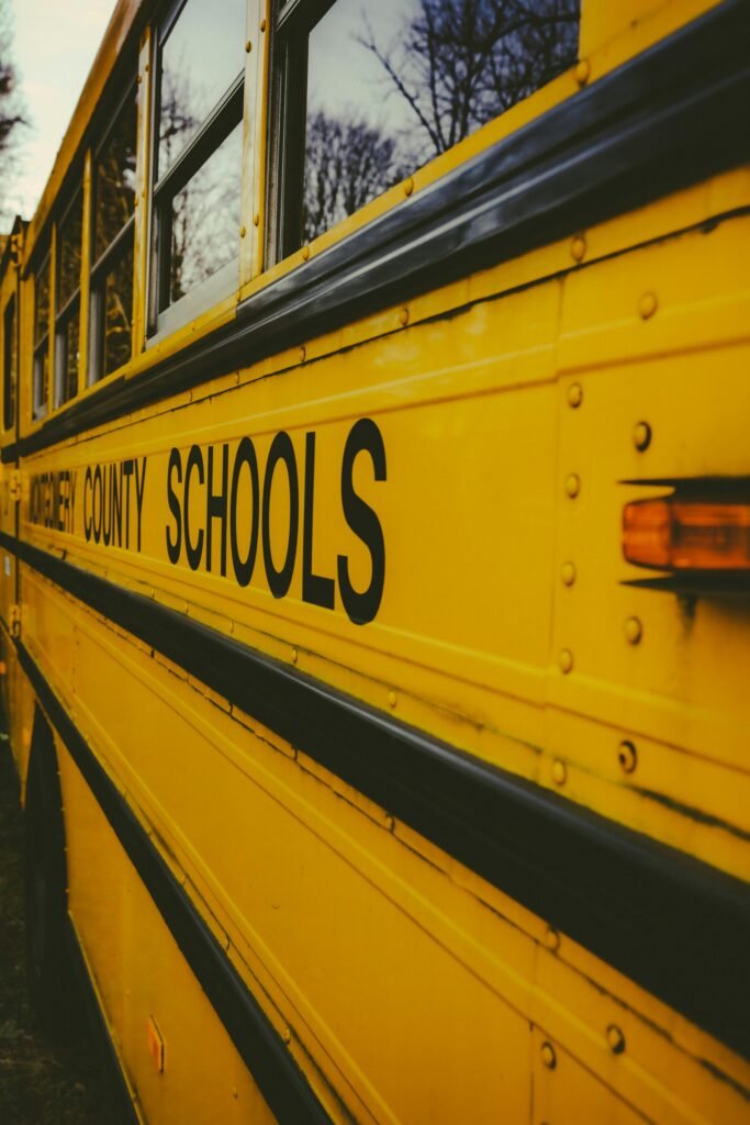 Close-up of a classic yellow school bus with text 'county schools' visible, bathed in evening light.